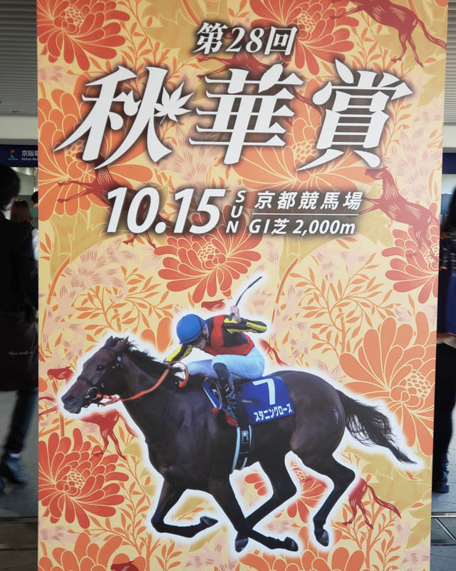 秋華賞の看板。「第28回秋華賞 10.15 SUN 京都競馬場 G1 芝2,000m」の文字と、7番のゼッケンをつけたスタニングローズ号と騎手の写真が載っている。